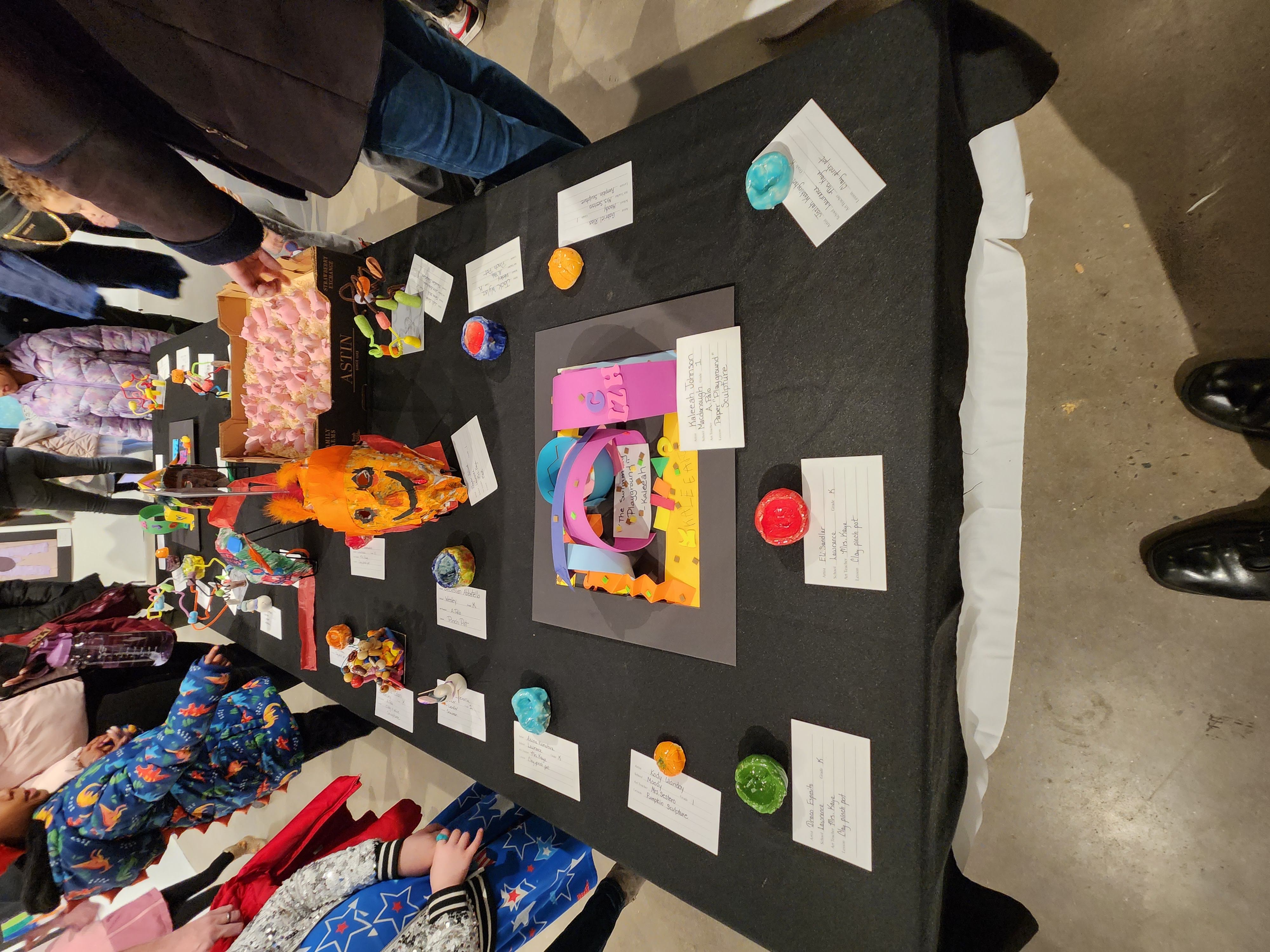 Visitors take in the pieces of artwork on display at one of the tables inside the gallery